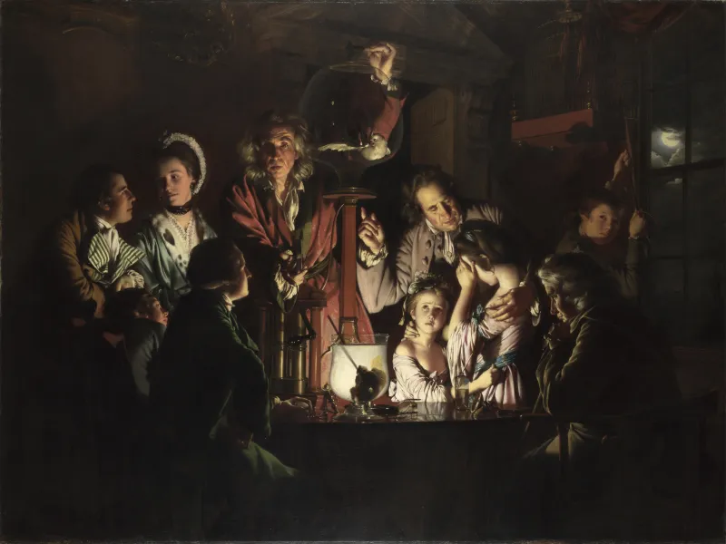 A dark candlelit painting of a night-time demonstration around a table: at the centre a long-haired man in a crimson robe faces the viewer with one hand at the top of a large glass globe in which a white cockatoo hangs with its wings spread; a dozen onlookers of various ages are ranged around him, two girls distressed and turned away, a young couple absorbed in each other, an old man seated at the right looking down at a large round glass vessel, lit from behind by the room's single candle, with a skull inside it, a boy at a window lowering a birdcage, and a full moon outside